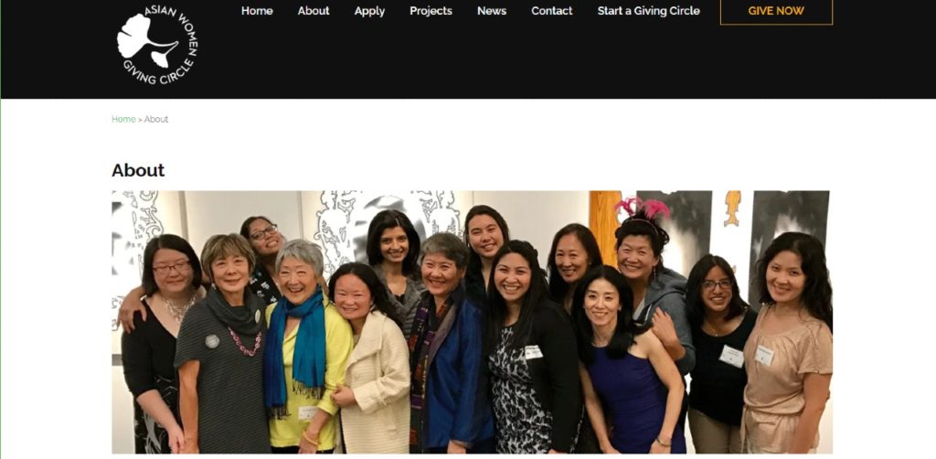 Photo of a what appears to be members of the AWGC, Asian Women Giving Circle, gathered in front of a few pieces of art.