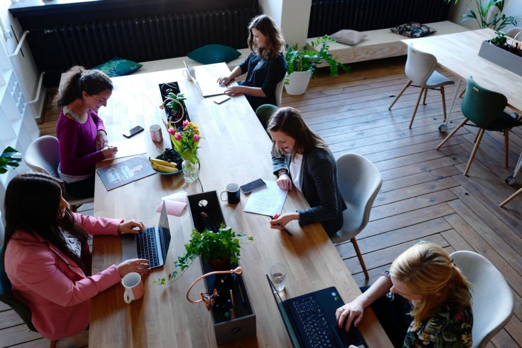 Five women sitting and working at a long table.